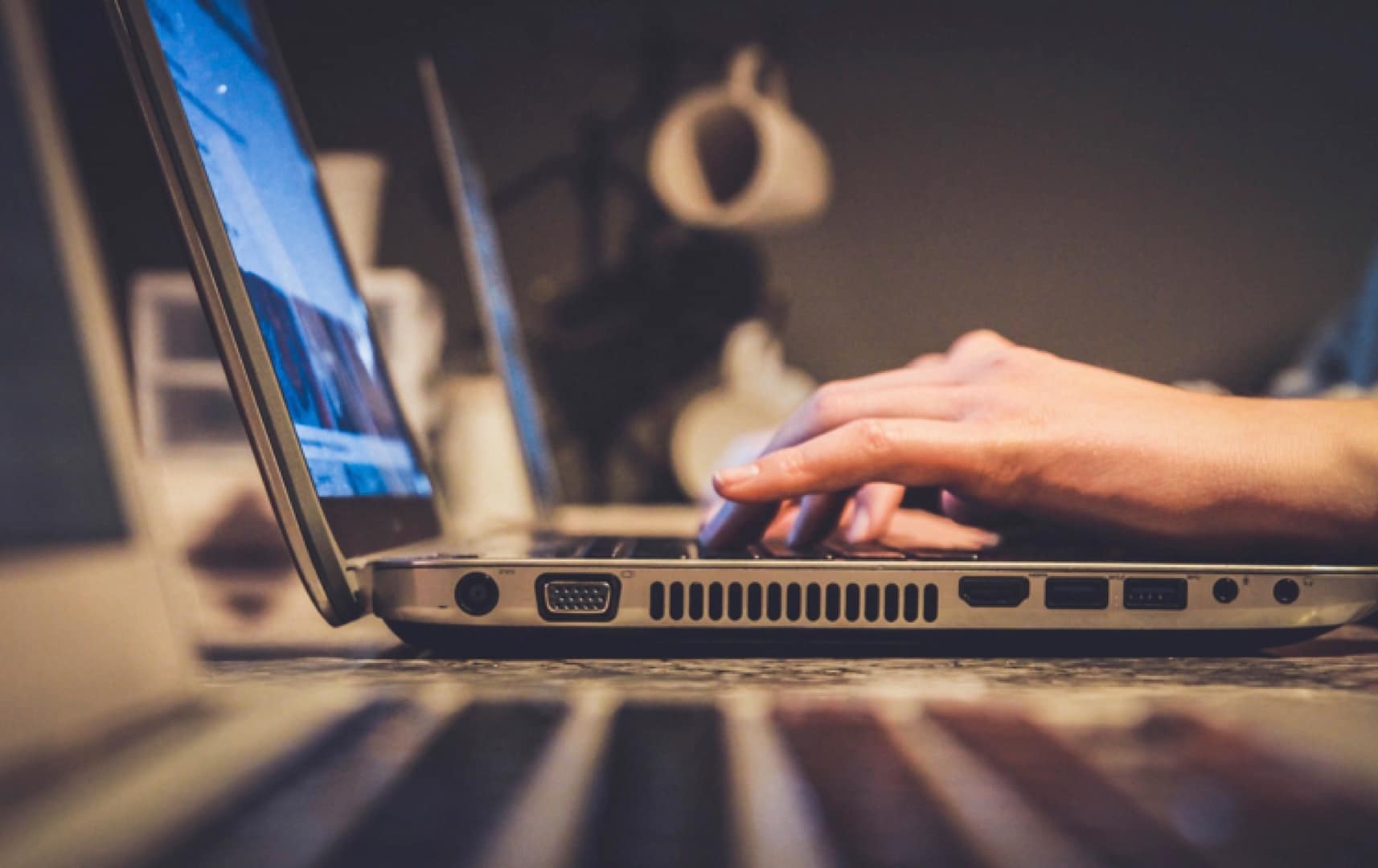 Someone unseen, typing on a laptop