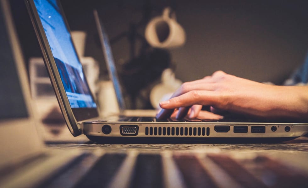 Someone unseen, typing on a laptop