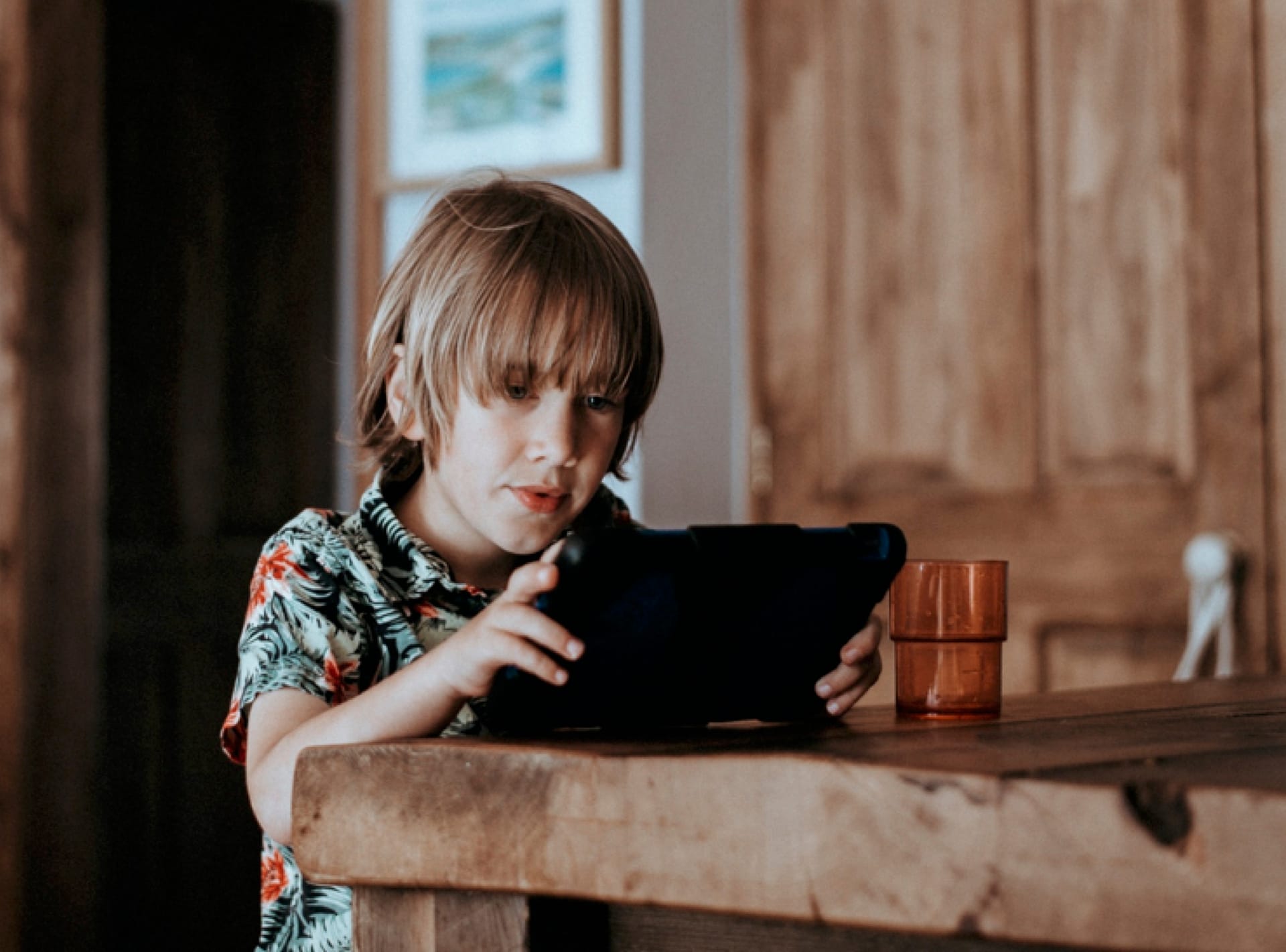 A boy sitting at a table using an iPad